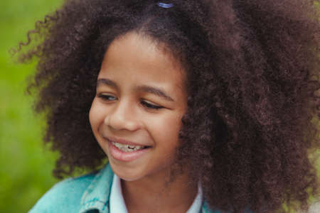 Outdoor portrait of lovely girl with bright smile and beautiful curly hair