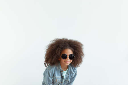 Cute stylish girl with beautiful curly hair wearing denim jacket and sunglassesの写真素材