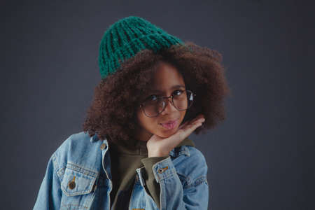 Cute girl wearing knit hat and casual clothes against black backgroundの写真素材