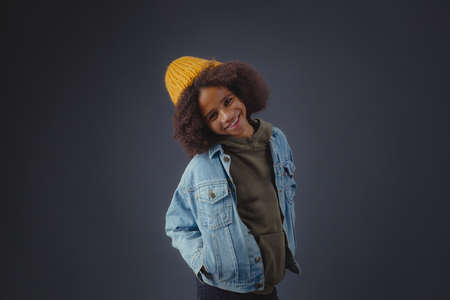 Lovely stylish teenage girl in denim jacket against dark backgroundの写真素材