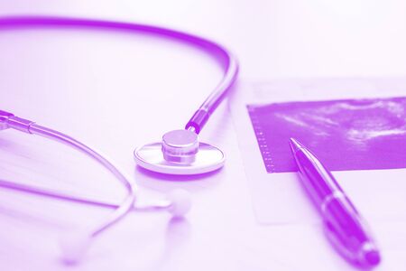 Medical desk on lilac backround with stethoscope, pen and fluoroscopic image, close up. Horizontal photoの写真素材