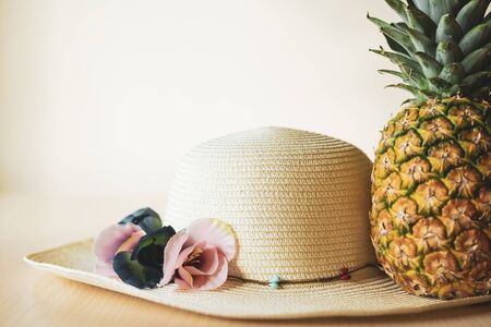 Straw hat and pineapple symbolize traveling to warm tropical countries. Color image, travel concept.の写真素材