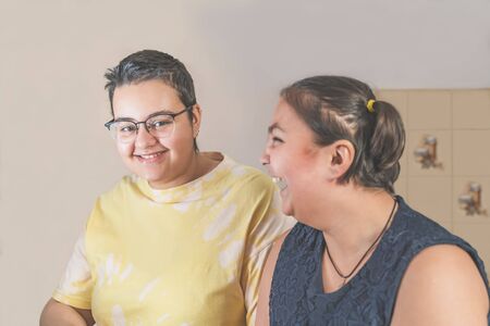 Older sister in glasses joking and making the younger one laughing.の写真素材