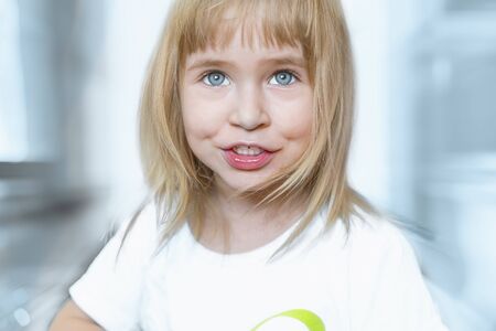 Portrait of charming little girl with blue eyes and blond hair. Charming child is smiling and happy. Extreme close up.の写真素材