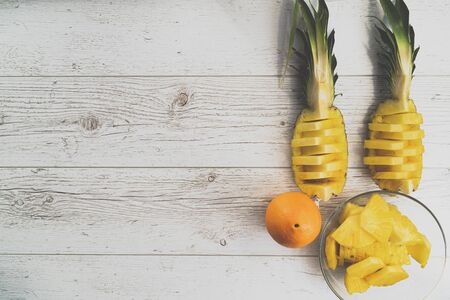 Pineapple slices and orange on wooden background. Tropical fruits. Healthy food concept. Top view and copy space.の写真素材