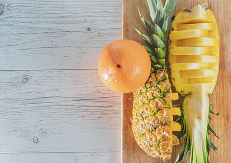 Pineapple slices and orange on wooden background. Tropical fruits. Healthy food concept. Top view and copy space.の写真素材