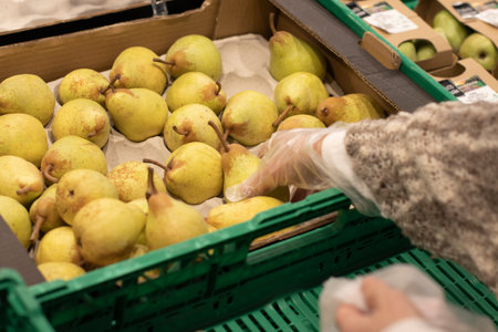 Woman putting pears in a plastic bag, in a market. Selective focus.の写真素材