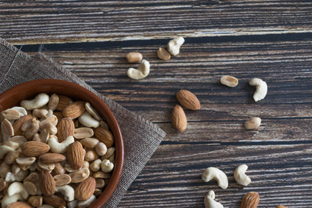 Mix of nuts in bowl on wooden background. Healthy food concept.