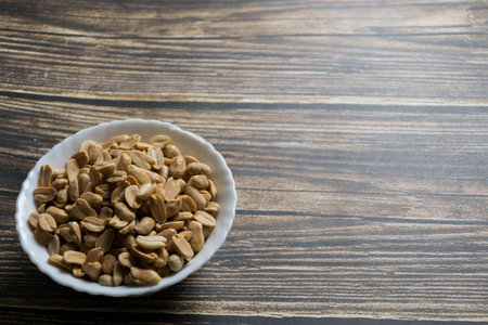 Peanuts in a white bowl on a wooden background. Copyspace.