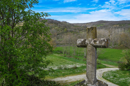 Old stone cross on a rural road in the middle of the forest