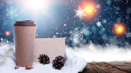 Hot coffee on a wooden table against the background of a winter landscape in a winter snowy forest. Coffee on the background of winter mountains. Snowflakes, frost.の写真素材