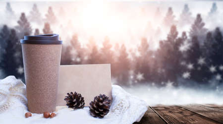 Hot coffee on a wooden table against the background of a winter landscape in a winter snowy forest. Coffee on the background of winter mountains. Snowflakes, frost.の写真素材