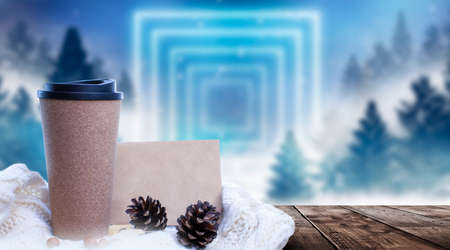 Hot coffee on a wooden table against the background of a winter landscape in a winter snowy forest. Coffee on the background of winter mountains. Snowflakes, frost.の写真素材