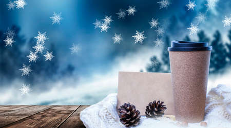 Hot coffee on a wooden table against the background of a winter landscape in a winter snowy forest. Coffee on the background of winter mountains. Snowflakes, frost.の写真素材