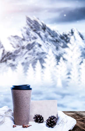 Hot coffee on a wooden table against the background of a winter landscape in a winter snowy forest. Coffee on the background of winter mountains. Snowflakes, frost.の写真素材
