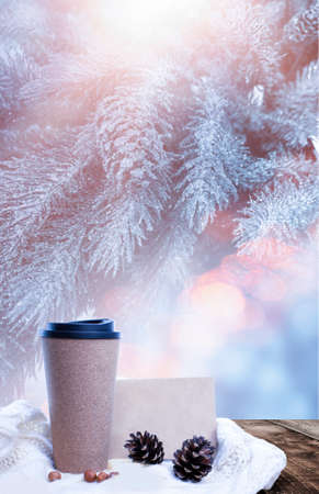 Hot coffee on a wooden table against the background of a winter landscape in a winter snowy forest. Coffee on the background of winter mountains. Snowflakes, frost.の写真素材