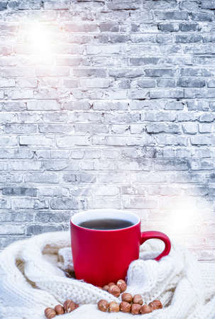 Red cup with coffee, tea on a snowy background, winter forest. A red cup against the background of a winter forest landscape on a soft, cozy scarf. Coffee, tea in the mountains.の写真素材