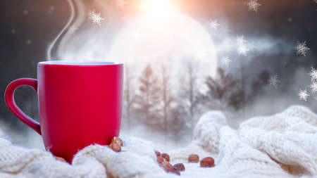 Red cup with coffee, tea on a snowy background, winter forest. A red cup against the background of a winter forest landscape on a soft, cozy scarf. Coffee, tea in the mountains.の写真素材