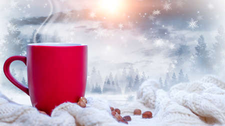 Red cup with coffee, tea on a snowy background, winter forest. A red cup against the background of a winter forest landscape on a soft, cozy scarf. Coffee, tea in the mountains.の写真素材