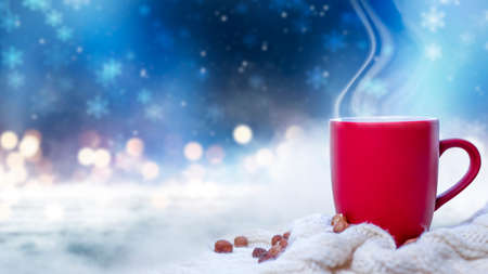 Red cup with coffee, tea on a snowy background, winter forest. A red cup against the background of a winter forest landscape on a soft, cozy scarf. Coffee, tea in the mountains.の写真素材