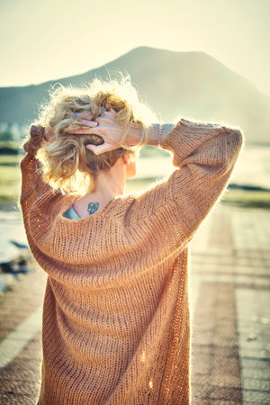 Back view of a young blonde woman with a tattoo in is nape outdoor.の写真素材