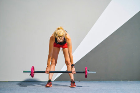 A woman is lifting a pink dumbbell. She is wearing a black tank top and red shorts. Fitness concept.の写真素材