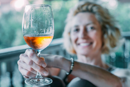 A woman is holding a wine glass and smilingの写真素材