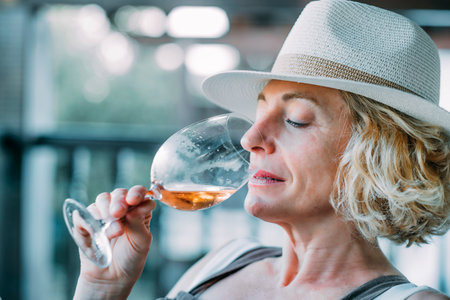 A woman in a straw hat is drinking from a wine glass.の写真素材