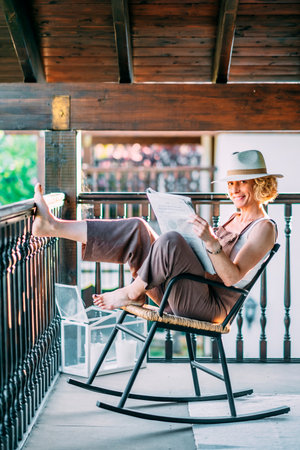 A woman is sitting on a chair reading a book.の写真素材
