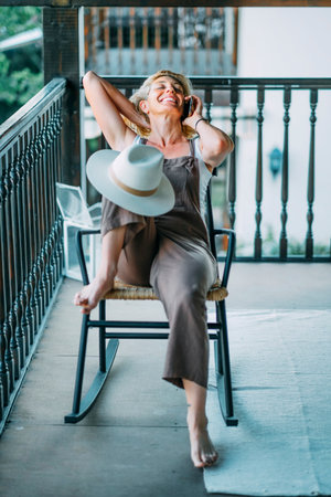 A woman wearing a hat is sitting on a rocking chair.の写真素材