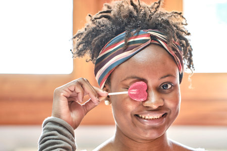 Young black woman with afro hair with a lollipop.の写真素材