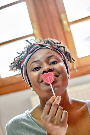 Young black woman with afro hair with a lollipop.