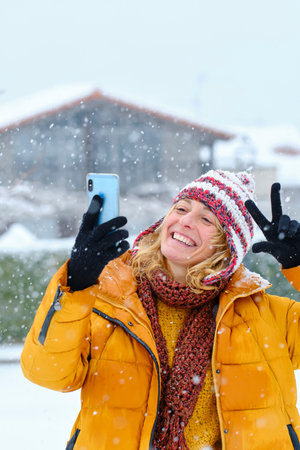Young woman with a mobile phone snow outdoor.の写真素材
