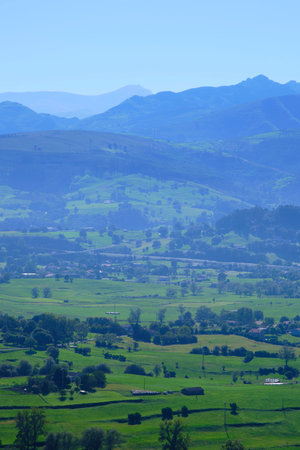 Breathtaking green valley surrounded by misty blue mountains in rural landscape