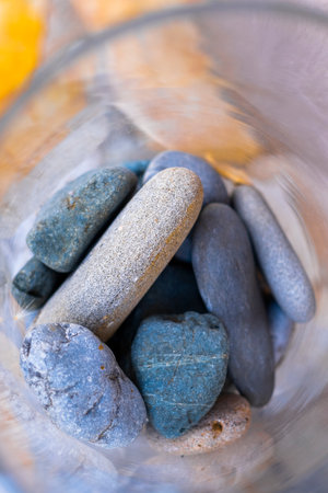 Glass filled with decorative river rocks creating soothing atmosphereの写真素材