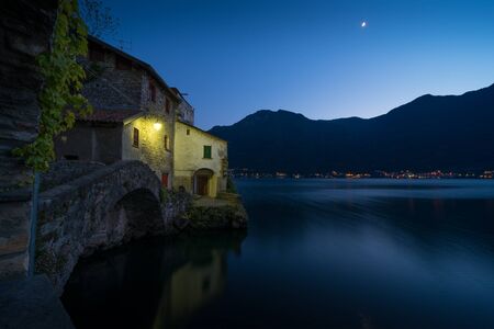 Scenic picture of Nesso on the Como lake in Italy with stone foreground at the blue hourの写真素材
