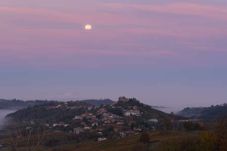 Full moon and pink clouds over Mornico Losana in Oltrepo Pavese during autumnの写真素材