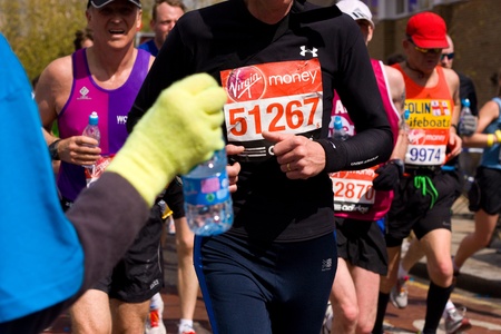 LONDON - APRIL 22: Volunteer giving water to runners at the London marathon on April 22, 2012 in London, England, UK. The marathon is an annual event.のeditorial素材