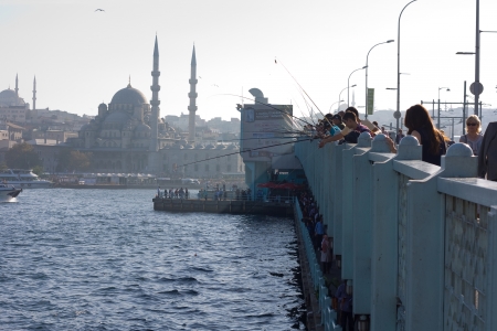 ISTANBUL - OCT 15TH: Unidentified people fish off the galata bridge on the 15th of April 2013 in Istanbul, Turkey. The galata bridge is a tourist landmark that attracts fisherman.のeditorial素材