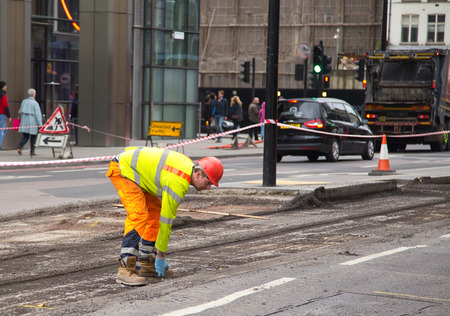 LONDON - OCTOBER 18TH: Unidentified workman resurfacing a road on October 18th, 2014 in London, England, UK. The city council carry's out annual road condition surveysのeditorial素材