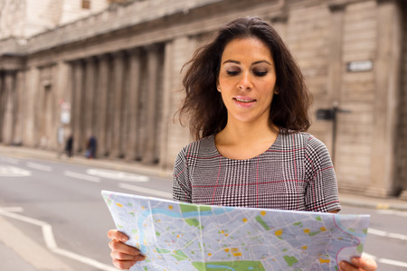 young woman reading a map in the cityの写真素材