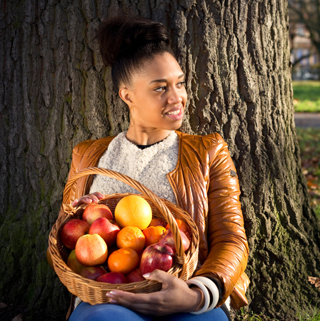 young woman holding a basket of fruitの写真素材