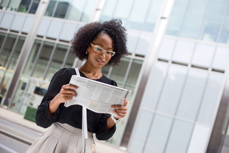 young office worker reading the paper in the streetの写真素材