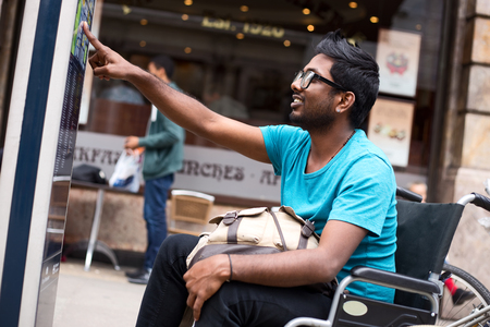 disabled man looking at a street map in his wheelchair.の写真素材