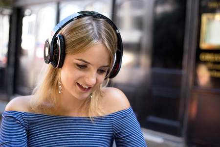young woman listening to music outside a barの写真素材