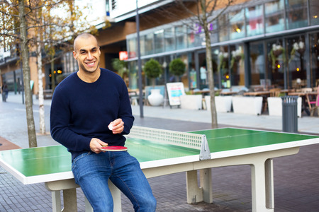 young man posing holding a table tennis racket and ballの写真素材