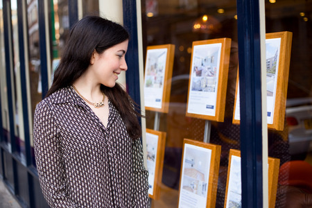 young woman looking in the window of an estate agentの写真素材