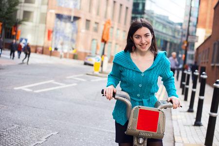 young woman riding a hire bike in the streetの写真素材