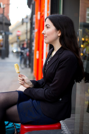 Young woman sitting in the street enjoying an ice-creamの写真素材