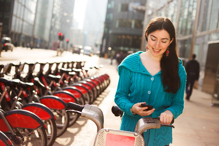Young woman with a hire bike checking her phoneの写真素材